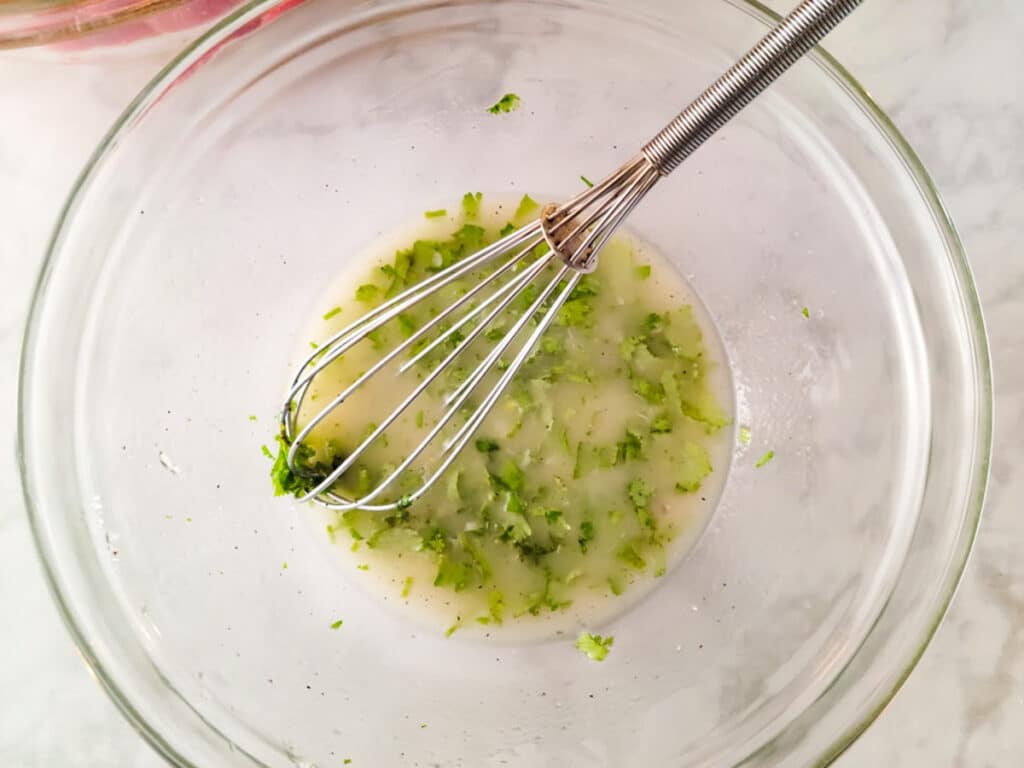 Garlic lime vinaigrette mixed in a white mixing bowl for the ensalada de garbanzo.