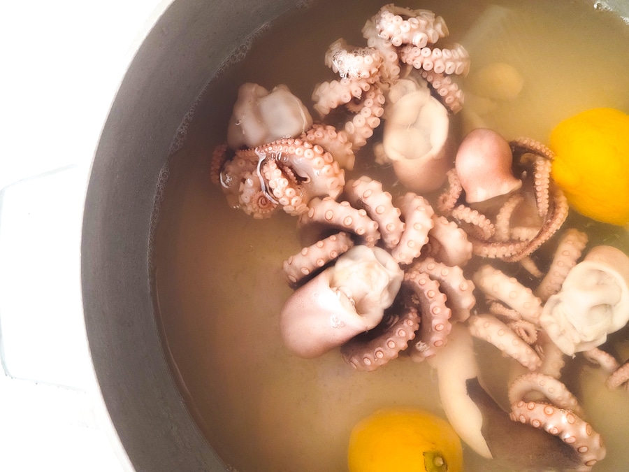 Baby octopus cooking in a pot with water, bay leaf, garlic, salt and lemon.