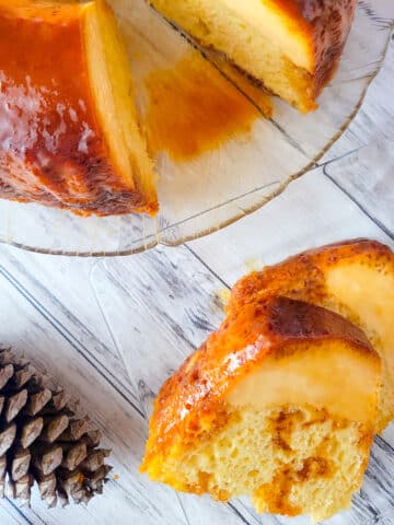 Flancocho (Vanilla Flan Cake) served on a white transparent platter with a serving on the side.