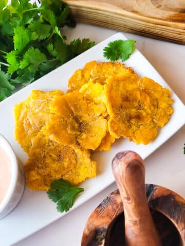 Puerto Rican garlic tostones served on a white platter with a side of mayoketchup.