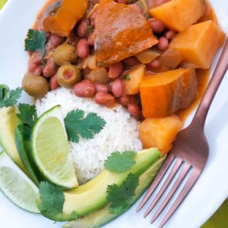 Habichuelas Guisadas con Calabaza served with white rice, avocado slices and lime wedges.