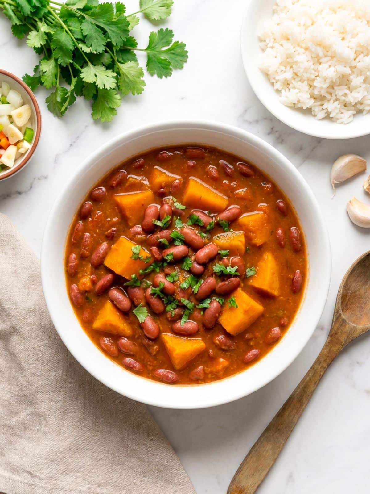 Habichuelas guisadas con calabaza served in a white bowl with a side of white rice and cilantro garnish.