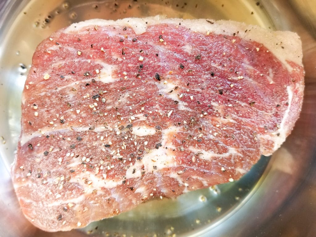 Seasoned uncooked beef round roast inside an instant pot.