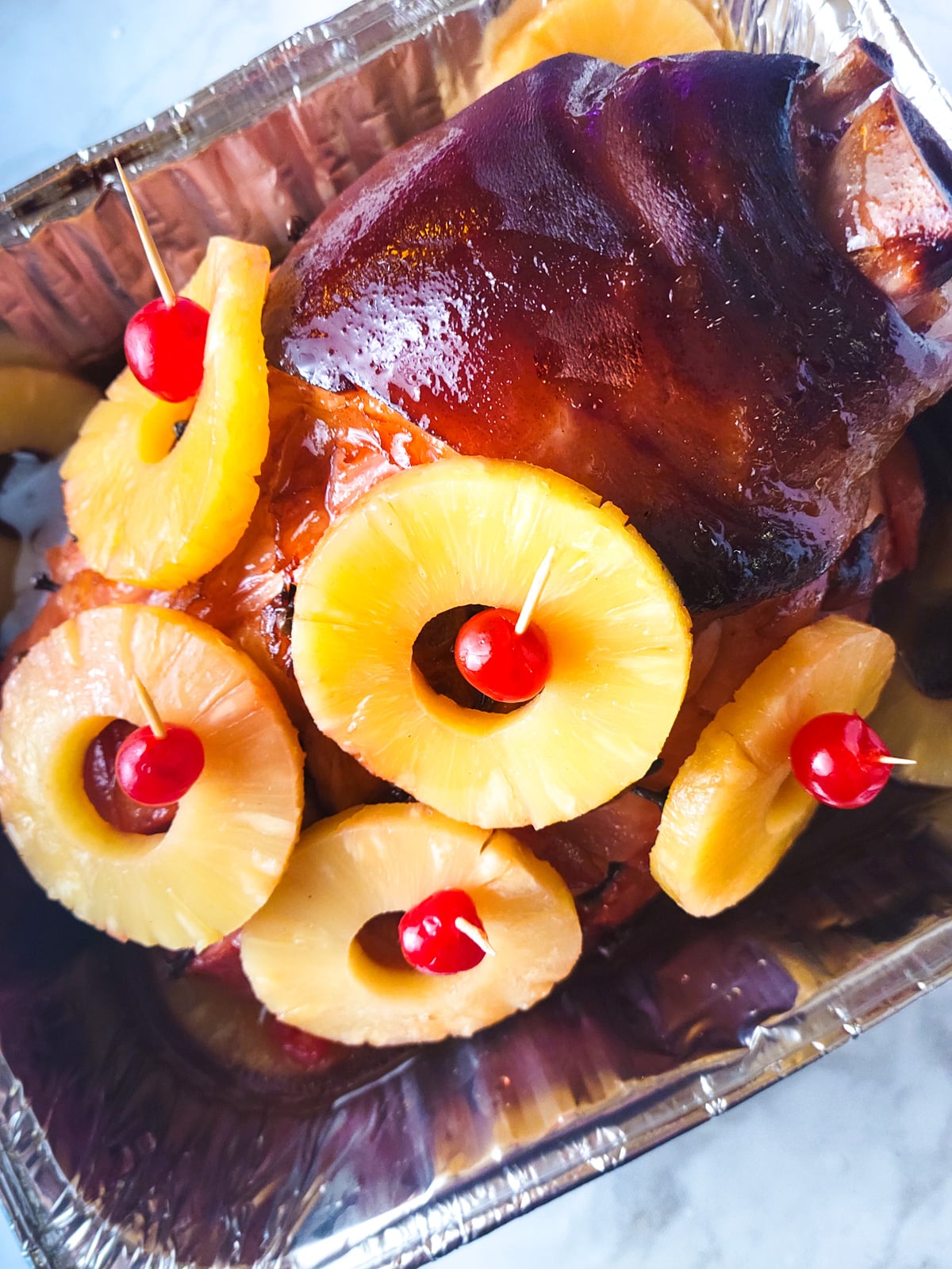 Pineapple slices and maraschino cherries topped on ham.