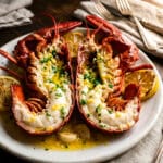 Langosta a la mantequilla, two lobster halves, served on a white platter with lemon wedges.