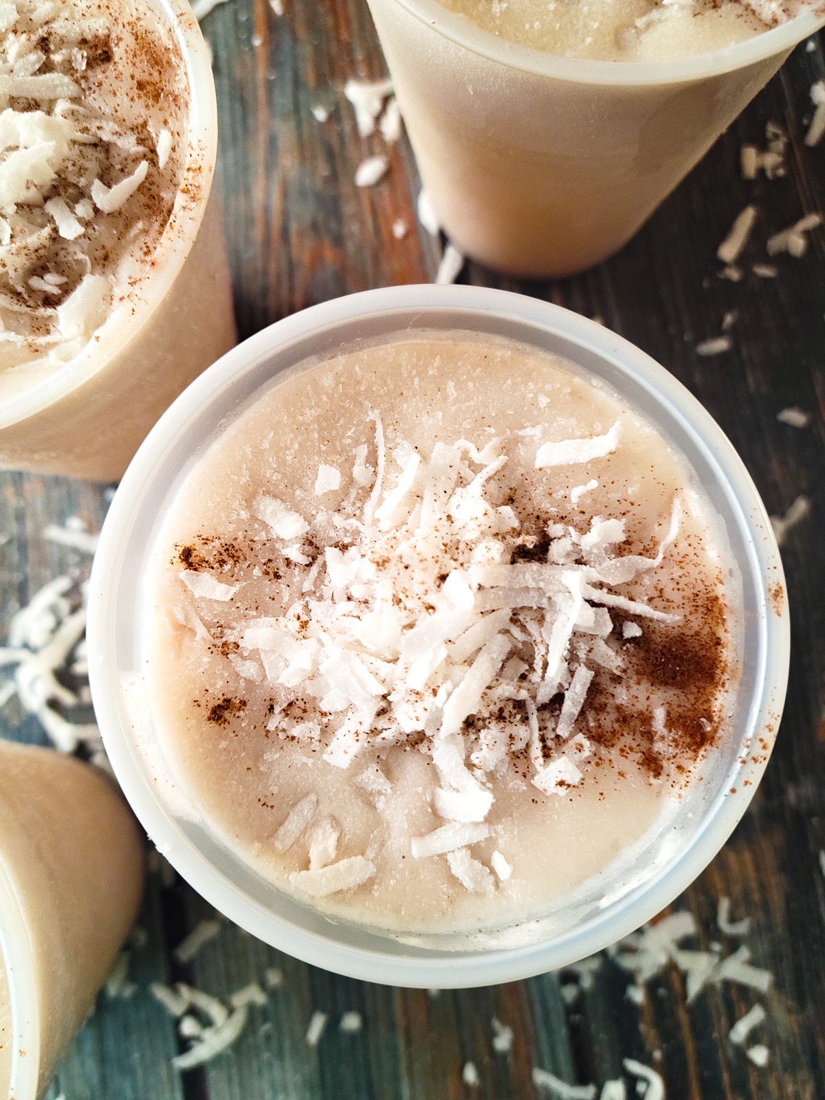 Limber de Coco (Coconut Limber) prepared and frozen in plastic cups, topped with shredded coconut and ground cinnamon.
