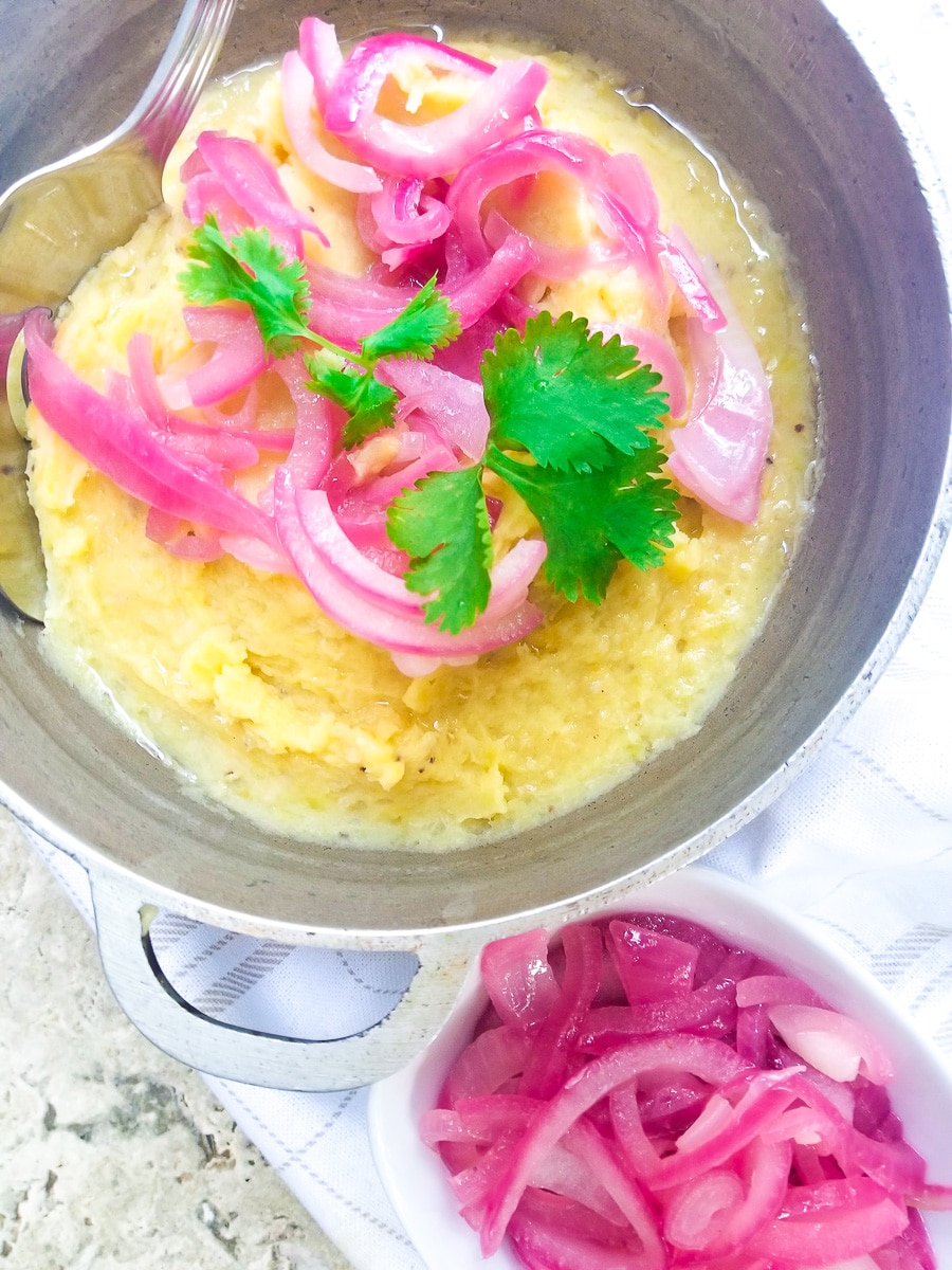 Mangu served in a caldero and topped with pickled onions with a side of more red onions.