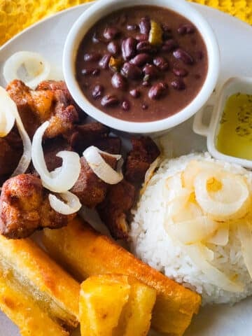Masitas de puerco served on a plate with a side of white rice and fried yuca.