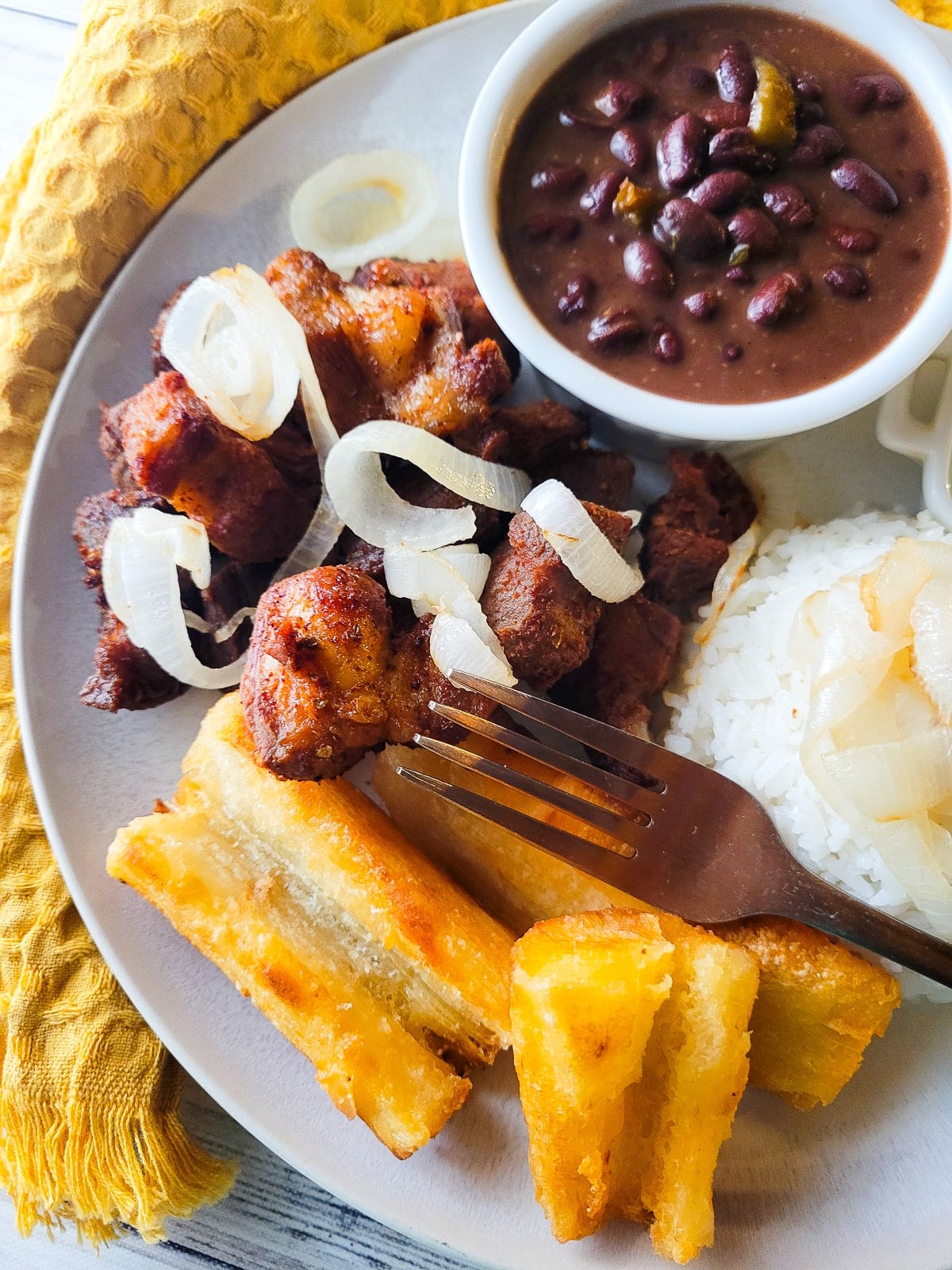 Masitas de puerco served on a plate with a side of white rice and fried yuca.