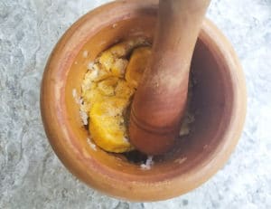 Plantain chunks in a mortar being mashed.