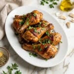 Muslos de pollo (chicken skillet drumsticks) served on a white oval platter.