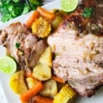 Paleta de Cerdo (Boston Butt) served on a white platter with potatoes, corn cobs, onions and carrots.