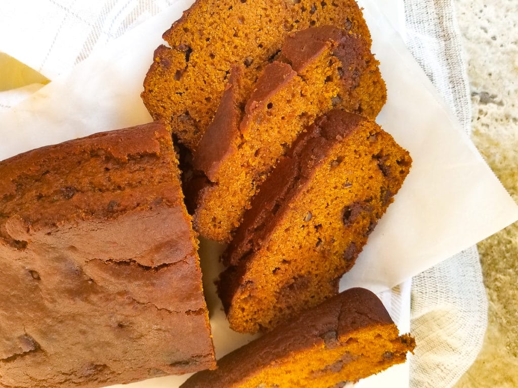 Pan de Calabaza (Pumpkin Bread) served on a white platter on top of white parchment paper.