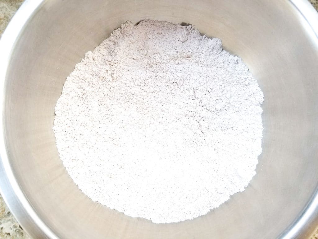 Flour, baking soda and pumpkin mix in a metal mixing bowl.