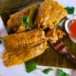 Pasteles de arroz (rice pasteles) served on a white plate with a side of hot sauce.