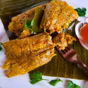 Pasteles de arroz (rice pasteles) served on a white plate with a side of hot sauce.