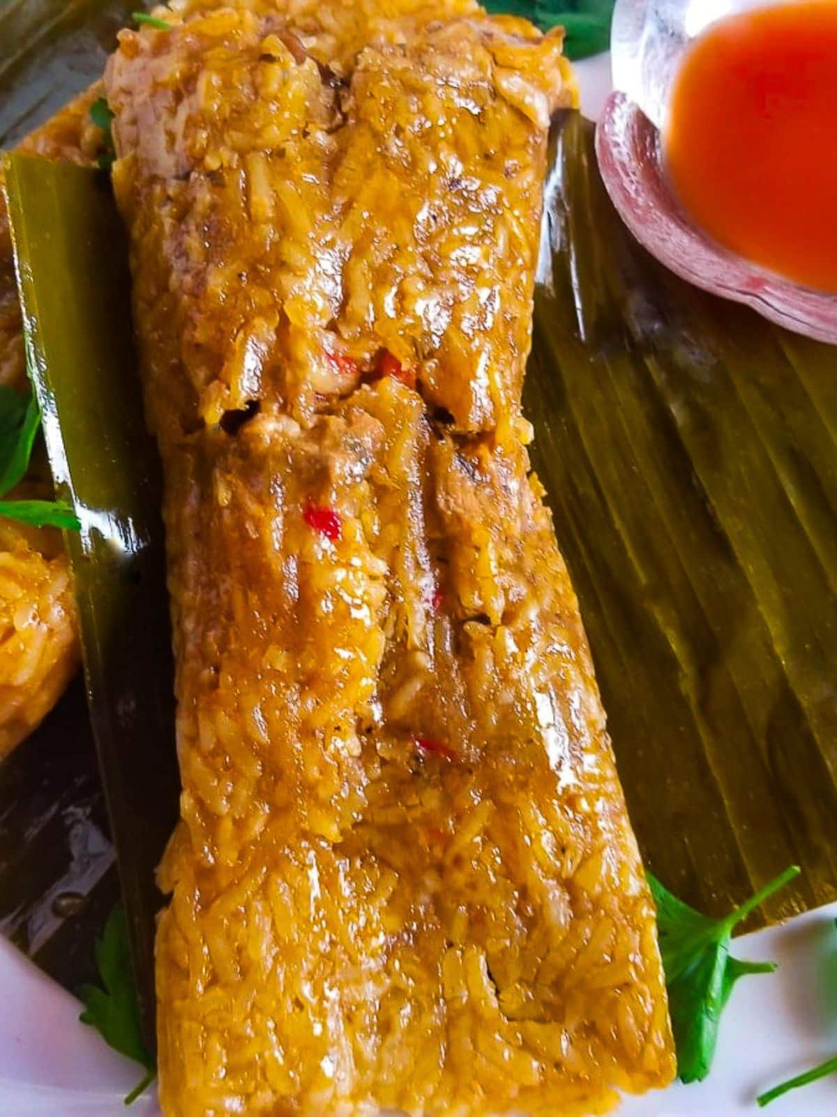 Pasteles de arroz (rice pasteles) served on a white plate with a side of hot sauce.