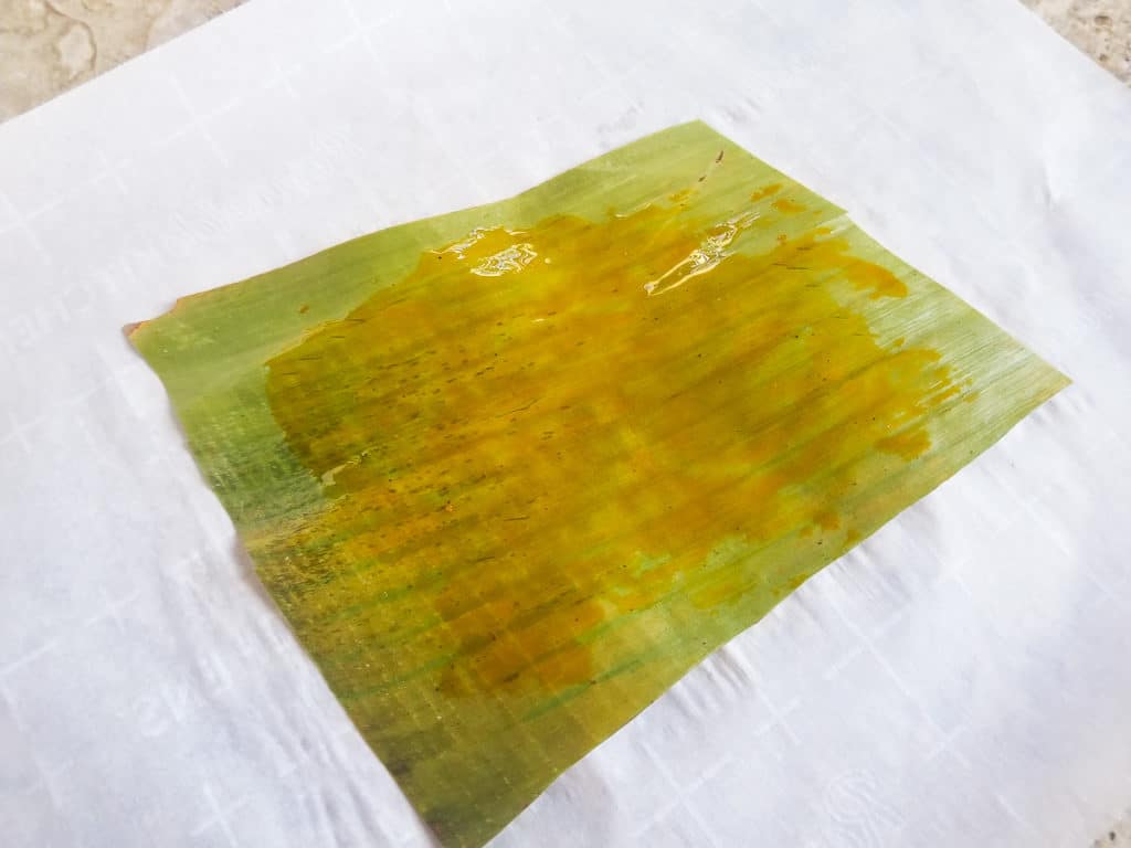 Achiote oil added to plantain leaf to make pastel de arroz (rice pastel).