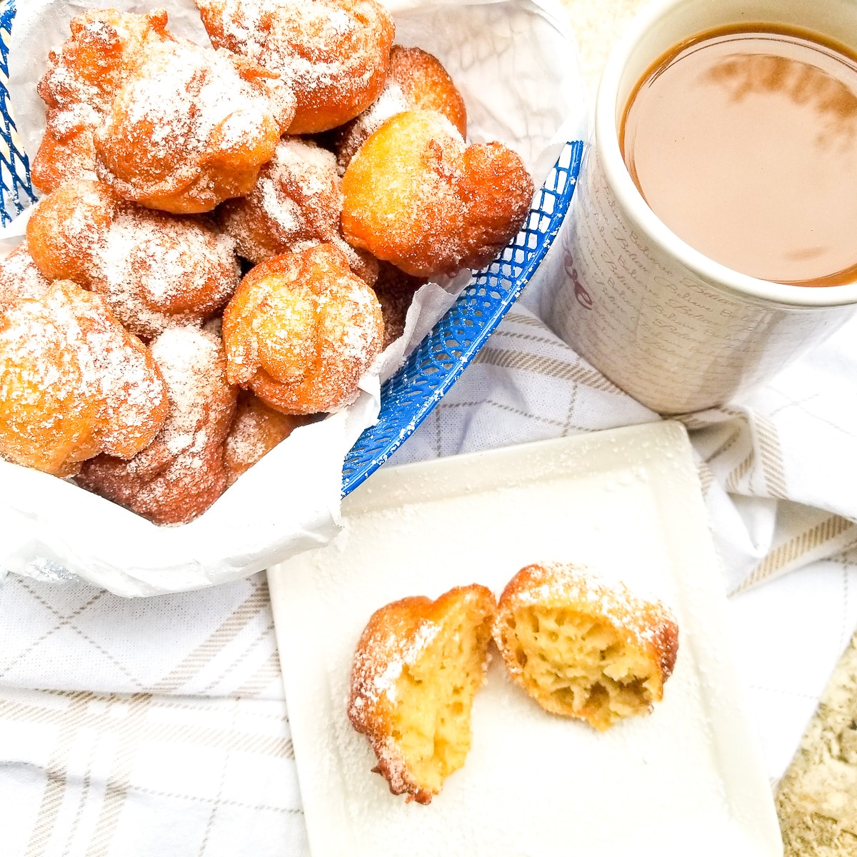 Plantain Puff Puffs served in a blue wire basket topped with confectioners sugar and coffee on the side.
