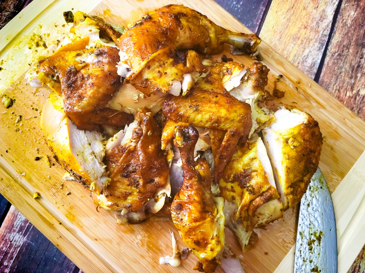 Quartered chicken on a wooden cutting board.