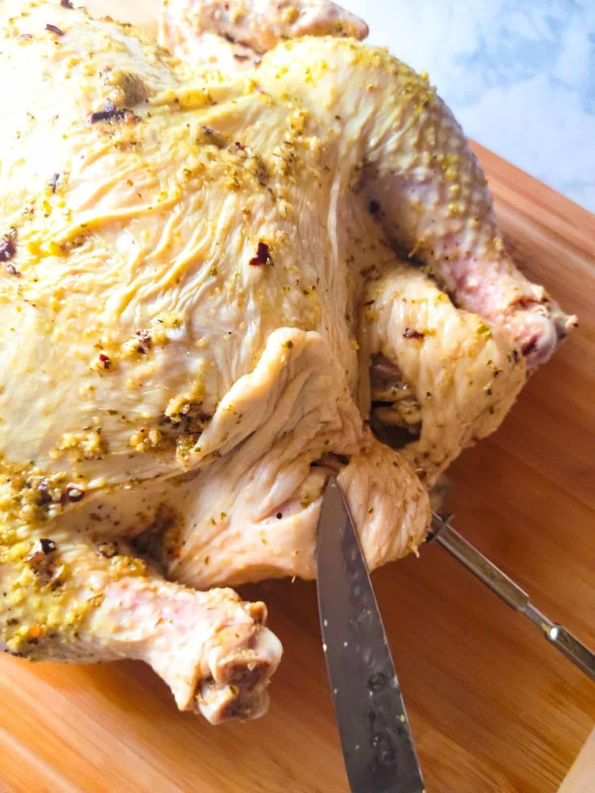 Showing how to make slits on chicken to tuck legs through without having to use kitchen twine.