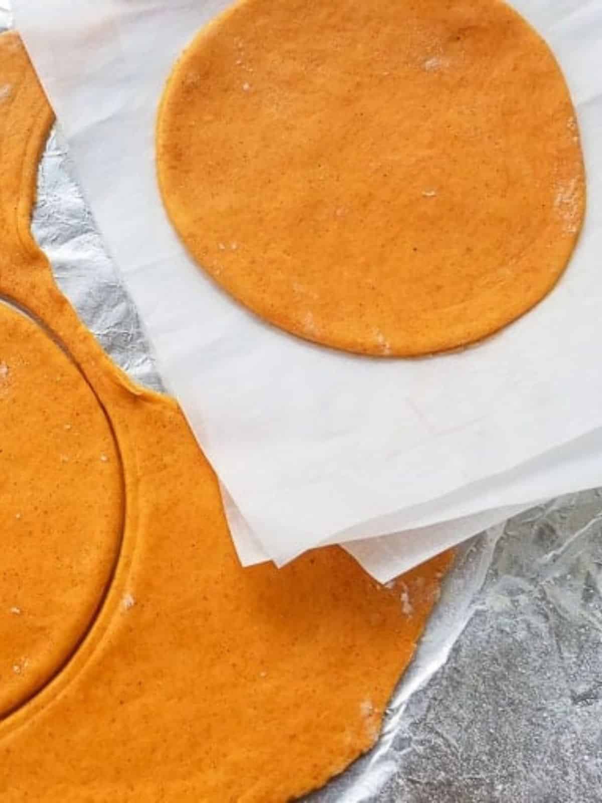 Masa de empanadillas rolled out and made into disks on counter top. Stored between parchment paper.