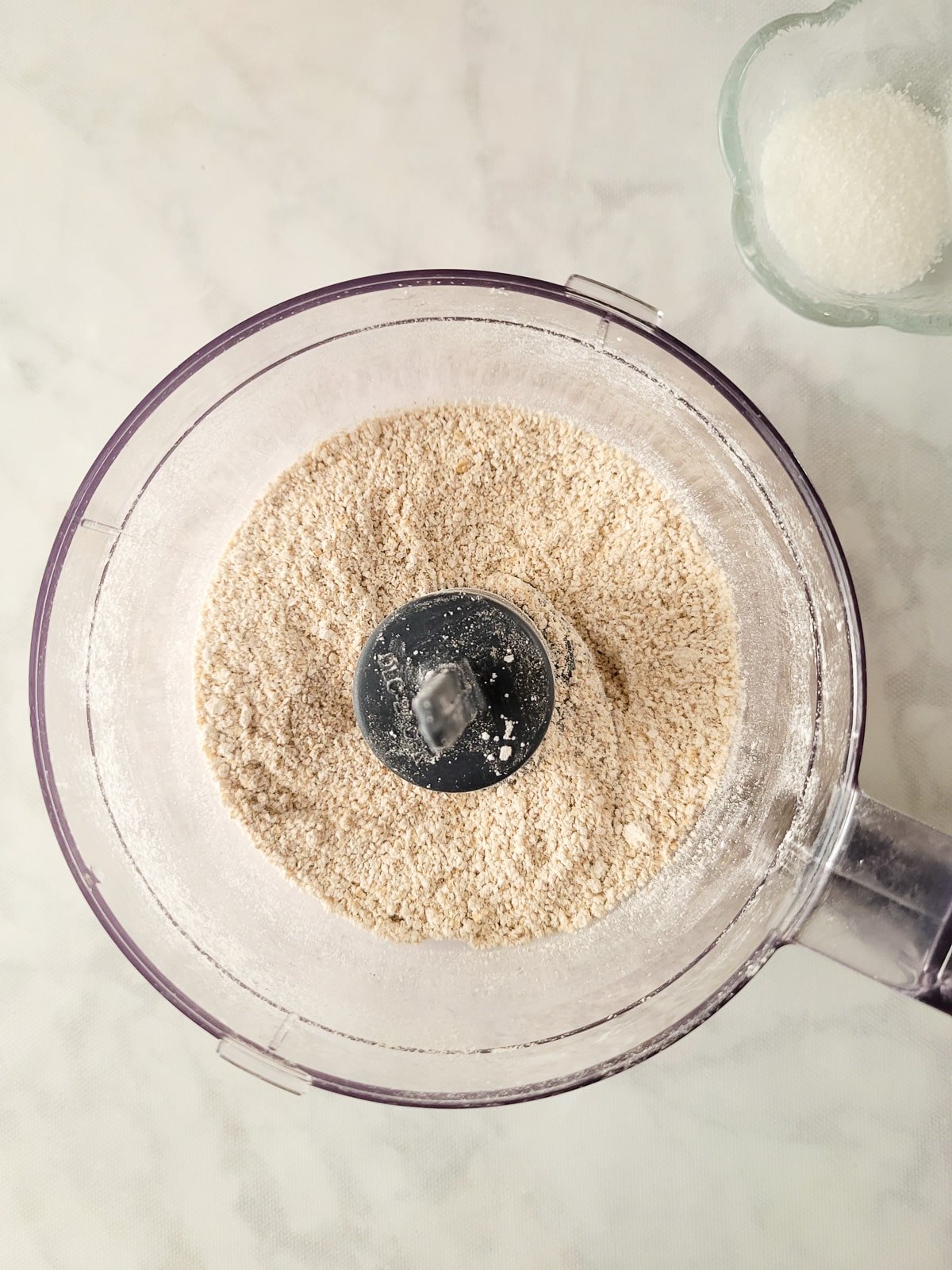Old fashioned oats added to a mini food processor to grind.