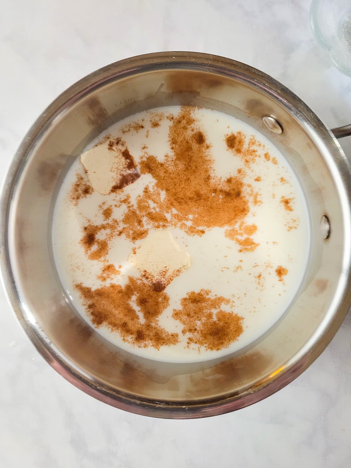 Milk. sugar, butter and cinnamon added to a saucepan.