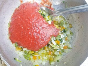 Tomato sauce added to the pot with all other ingredients for the salsa criolla (criolla sauce).