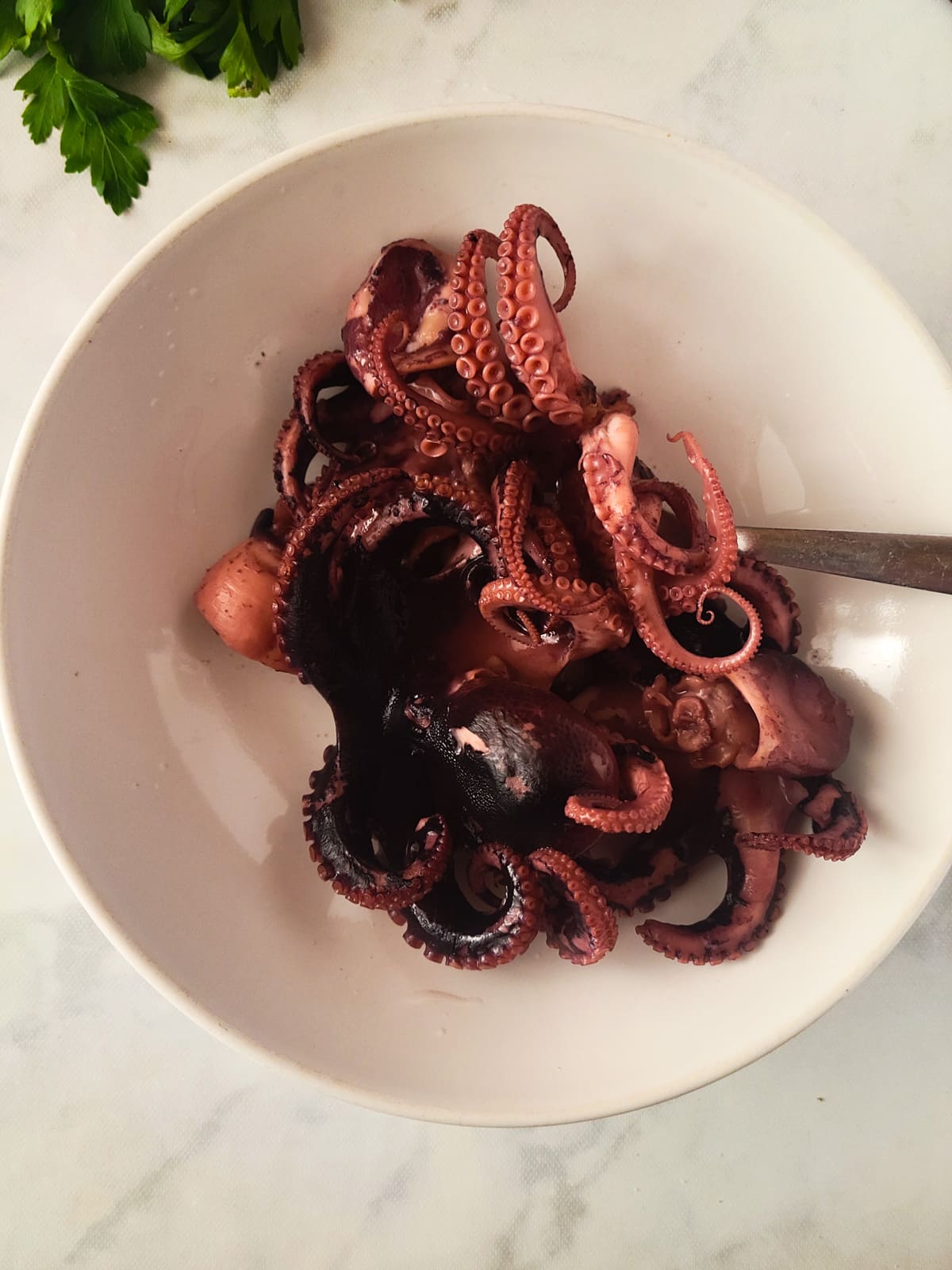 The cooked octopus in a white bowl.