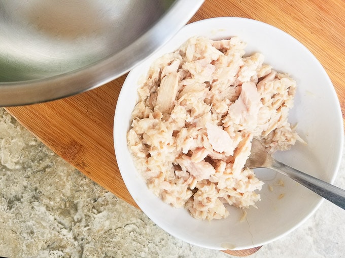 Drained tuna and flaked in a white bowl.