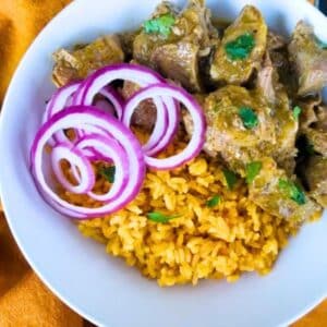 Slow Cooker Ribs with yellow rice and red onions on a white plate.