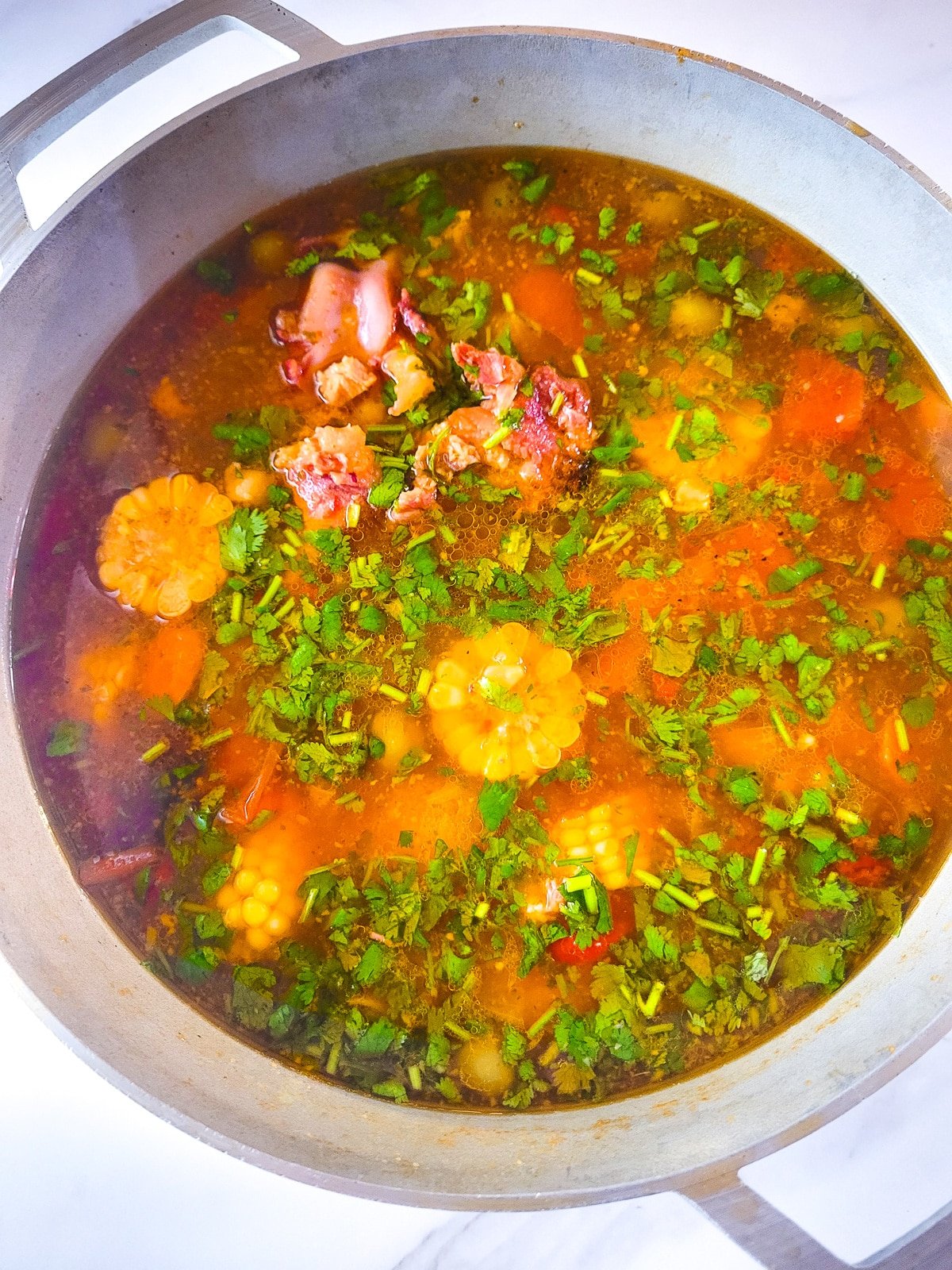 Fully cooked pot of sopa de jamón (Puerto Rican ham soup) in a large caldero.