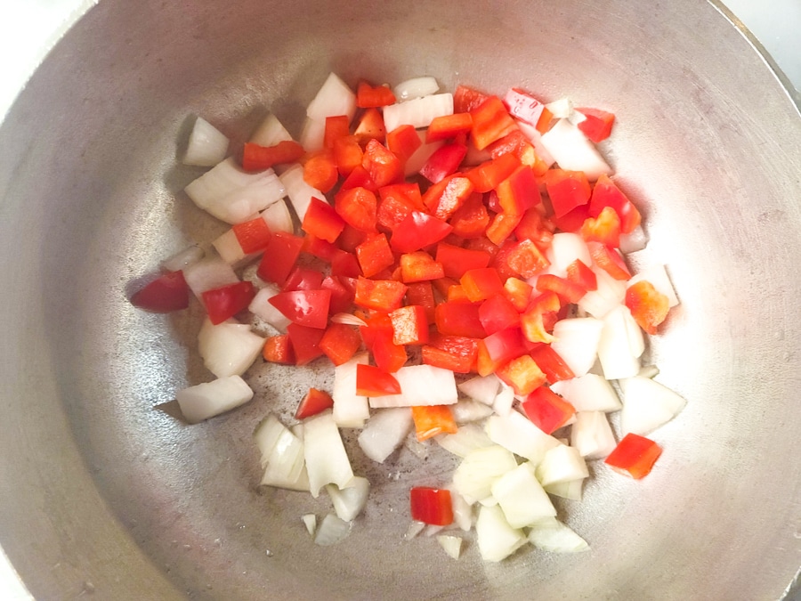 Onions and red peppers cooking in a caldero (dutch oven) pot.