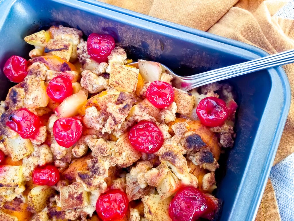 Sweet Potato Casserole served in a baking dish topped with pineapple chunks, butter crumble and maraschino cherries.