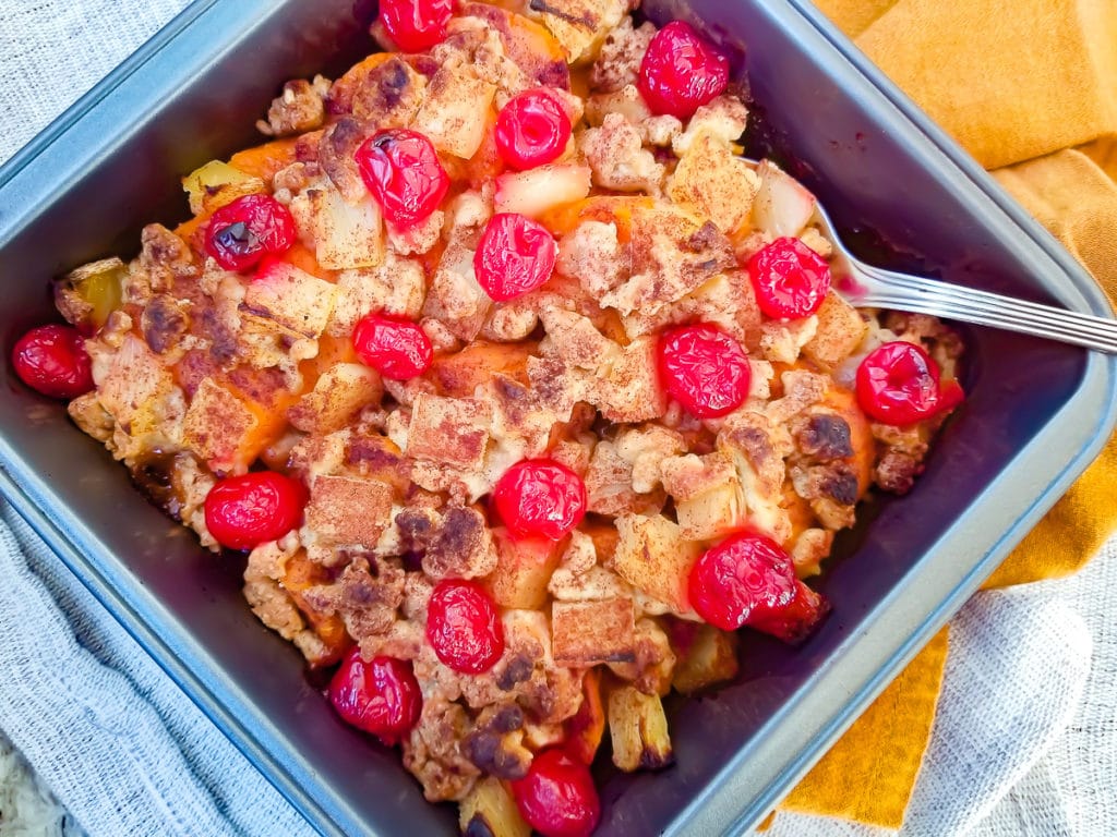 Sweet Potato Casserole served in a baking dish topped with pineapple chunks, butter crumble and maraschino cherries.