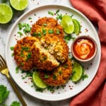 Tortitas de atun served on a white plate with lime wedges and a garlic aioli dipping sauce.