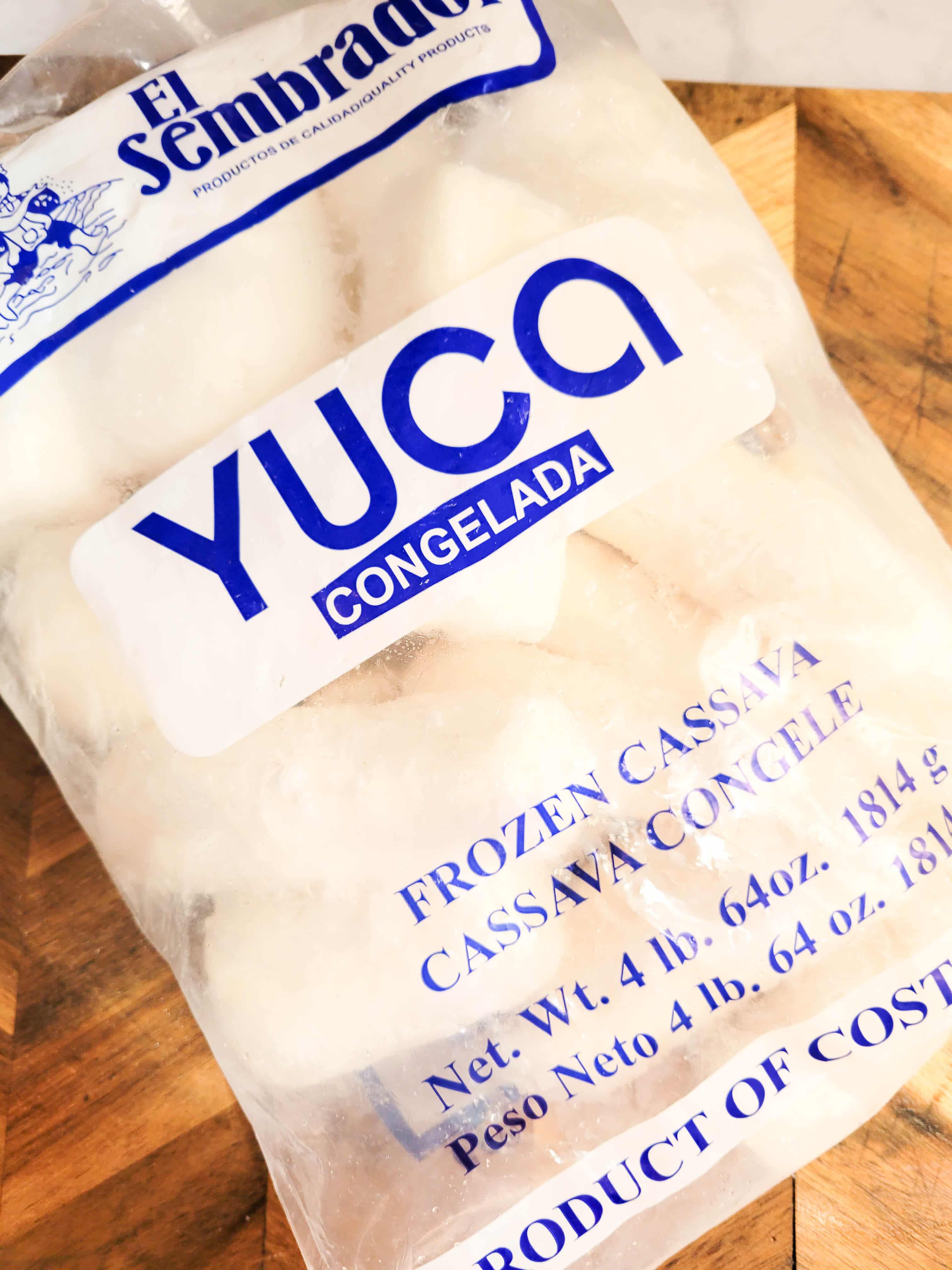 A bag of frozen yuca on a wooden cutting board.